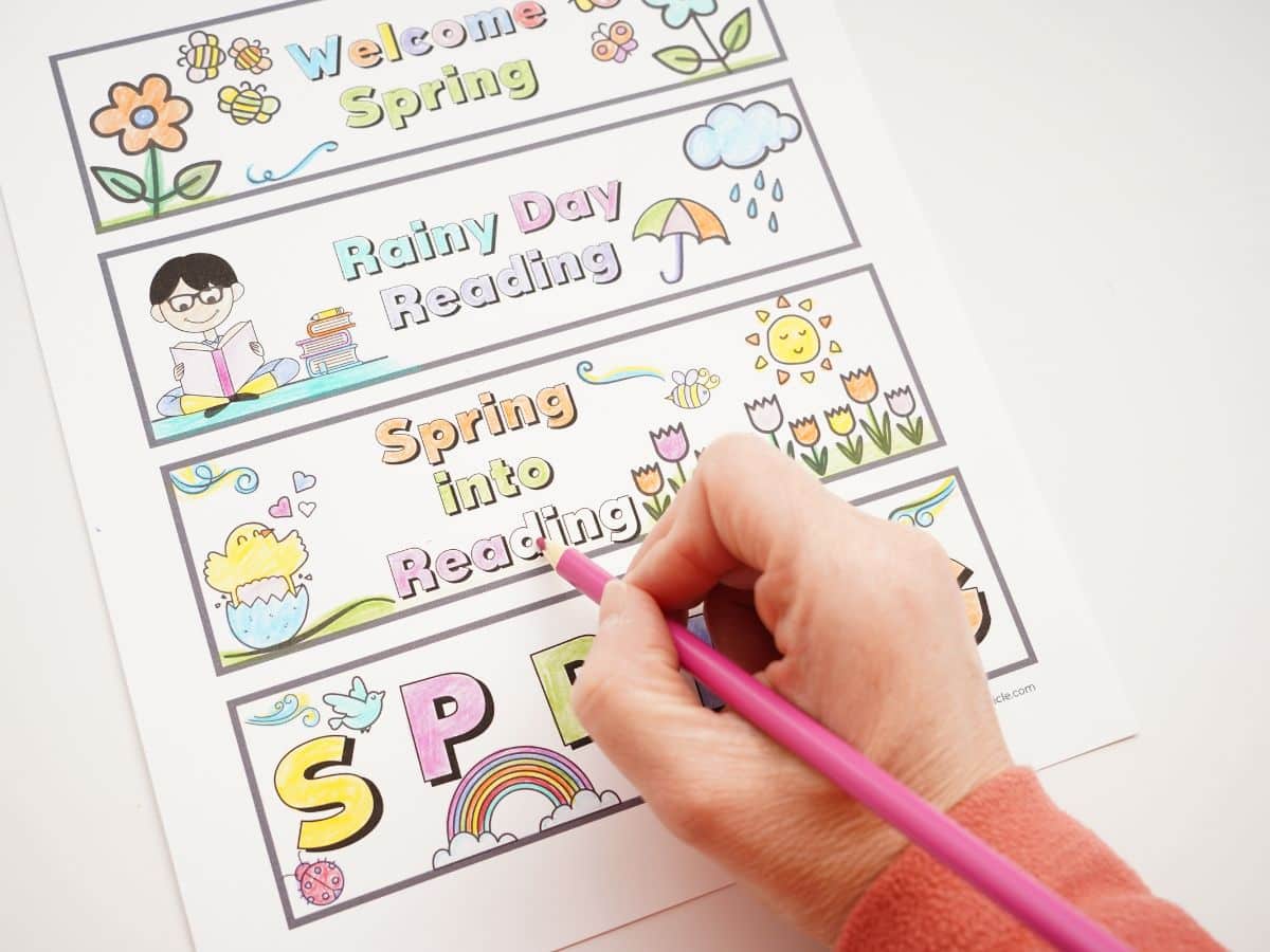 spring bookmarks being colored with pencil crayons with a hand