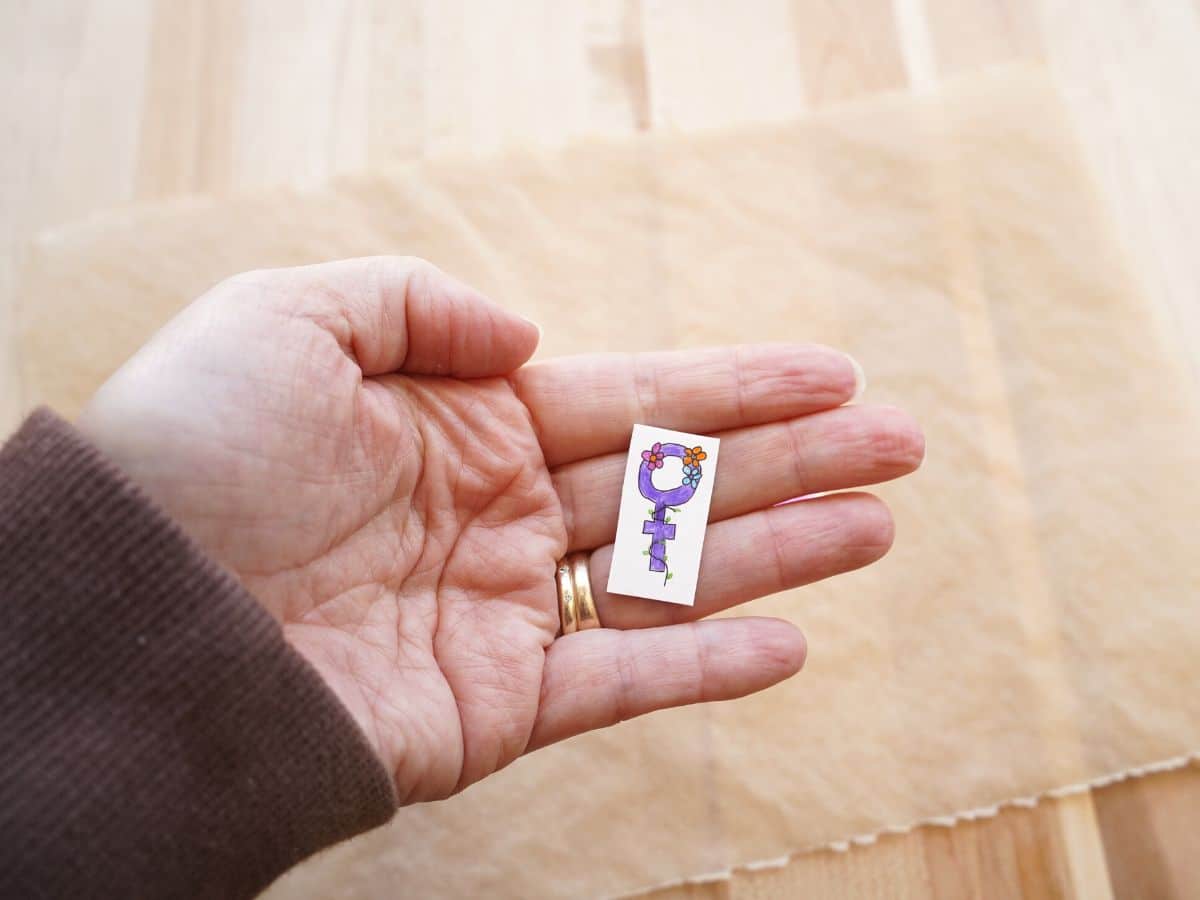 women symbol pin in woman's hand