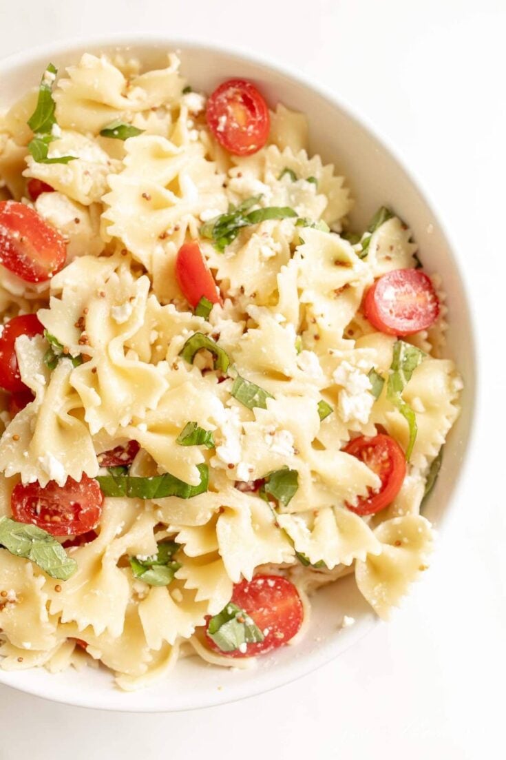 close up of bow tie pasta with cherry tomatoes and basil