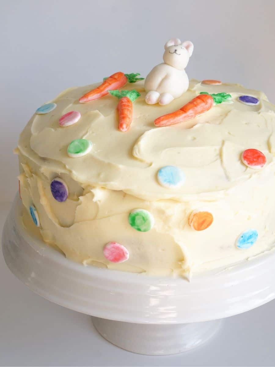 carrot cake with cream cheese frosting decorated with fondant bunny, carrots and dots