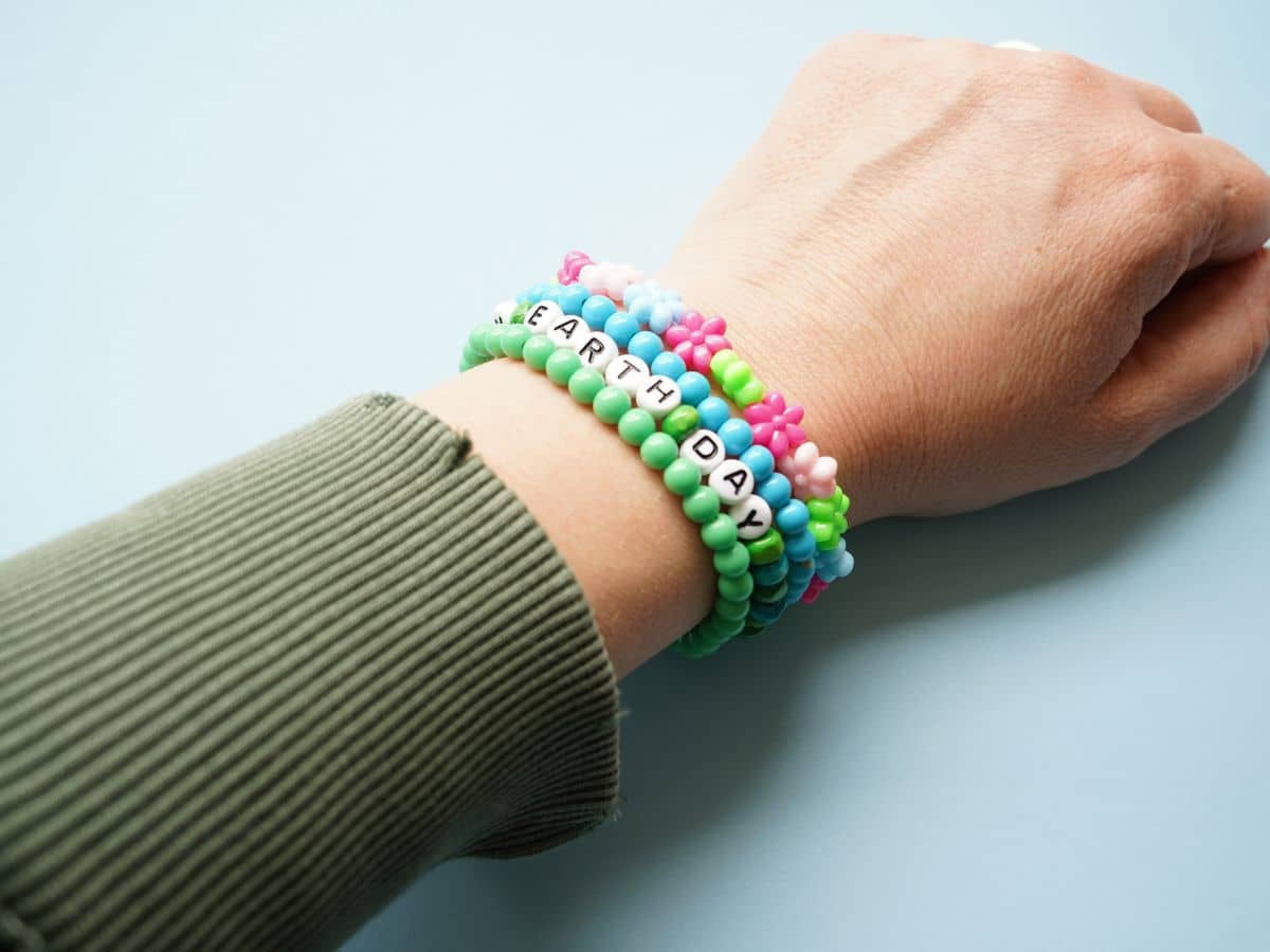 earth day bracelet on wrist with blue and green and flower bead bracelets