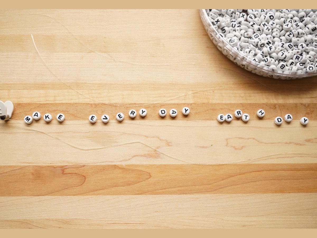 letter beads with words make every day earth day on wood table