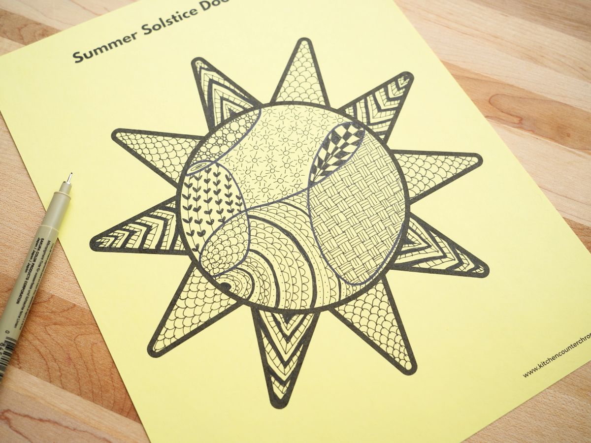 zentangle pattern filled sun template on table with black marker