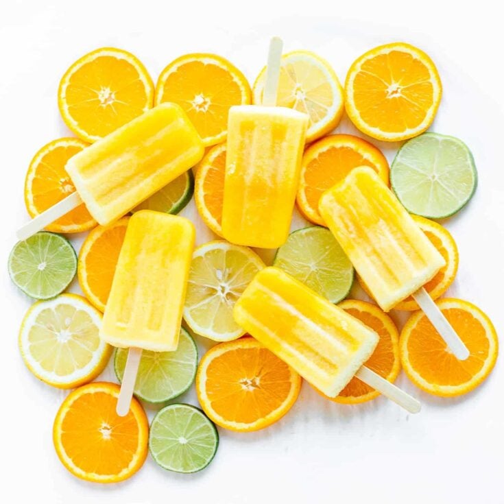orange lemon lime popsicles on top of sliced oranges, lemons and limes