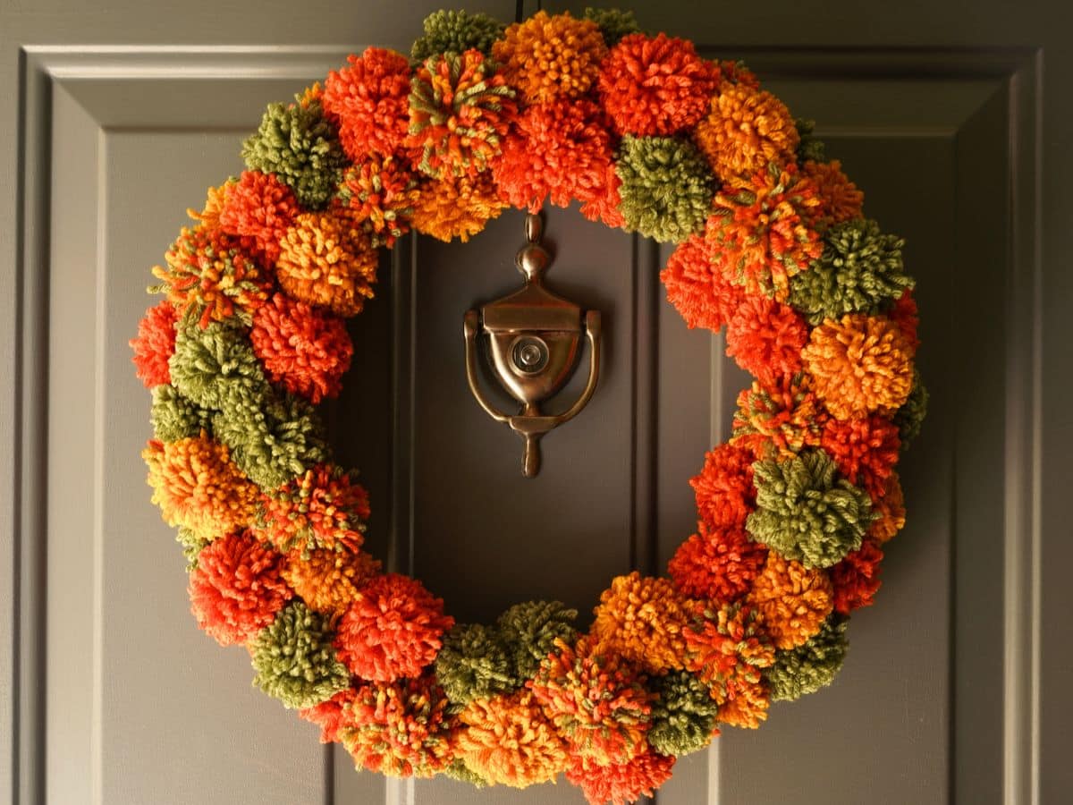 diy fall pompom wreath hanging on front door