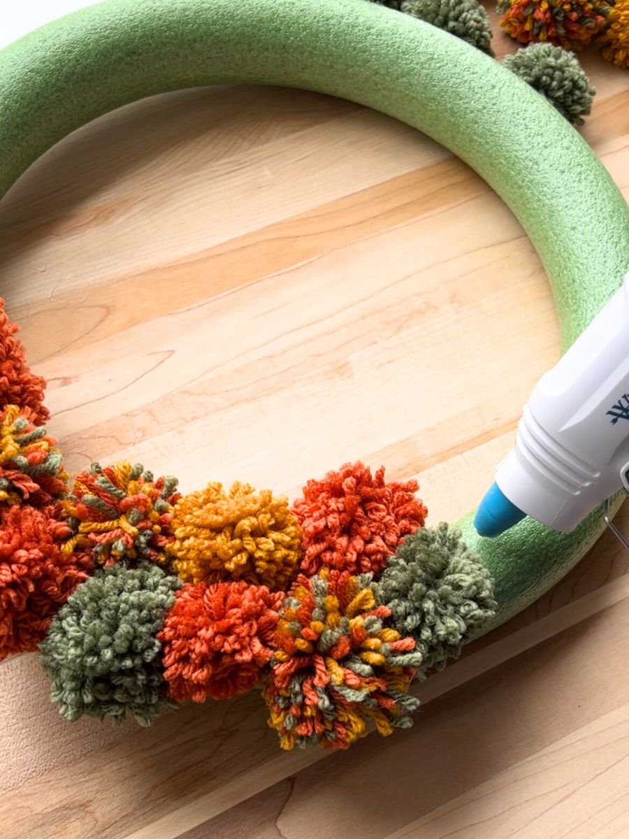 dollop of glue from glue gun on wreath form with pom poms