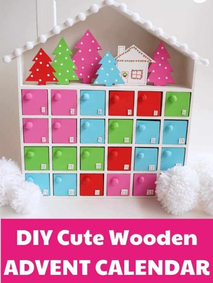 DIY Wooden advent calendar idea craft project - image of colorful painted wooden advent calendar with cardboard christmas trees and a cabin in the upper area of the calendar