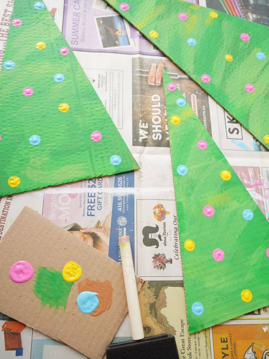 cardboard christmas trees on table with paint polka dot ornaments being painted on
