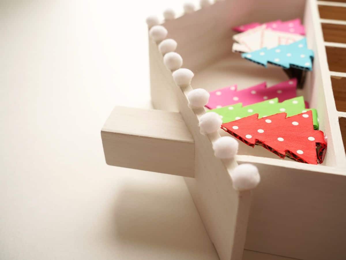 close up of white pom pom glued on edge of roof of advent calendar