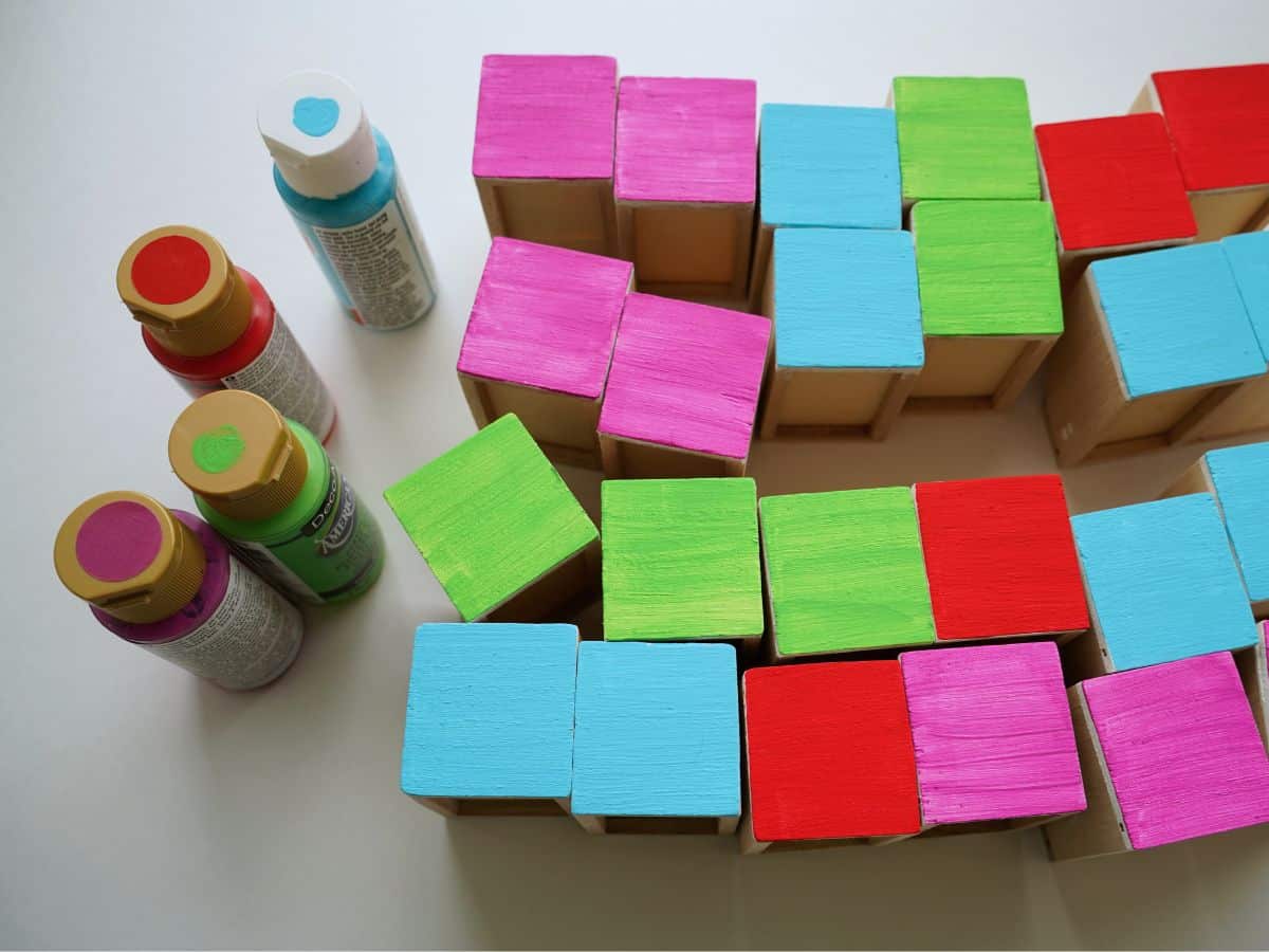 red paint, blue paint, green paint and pink paint beside wooden advent calendar drawers painted