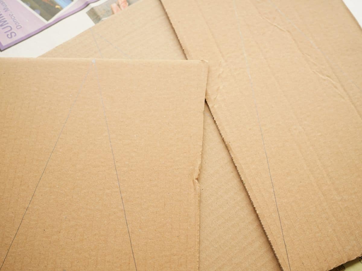 sheets of cardboard with christmas tree shapes drawn on with pencil