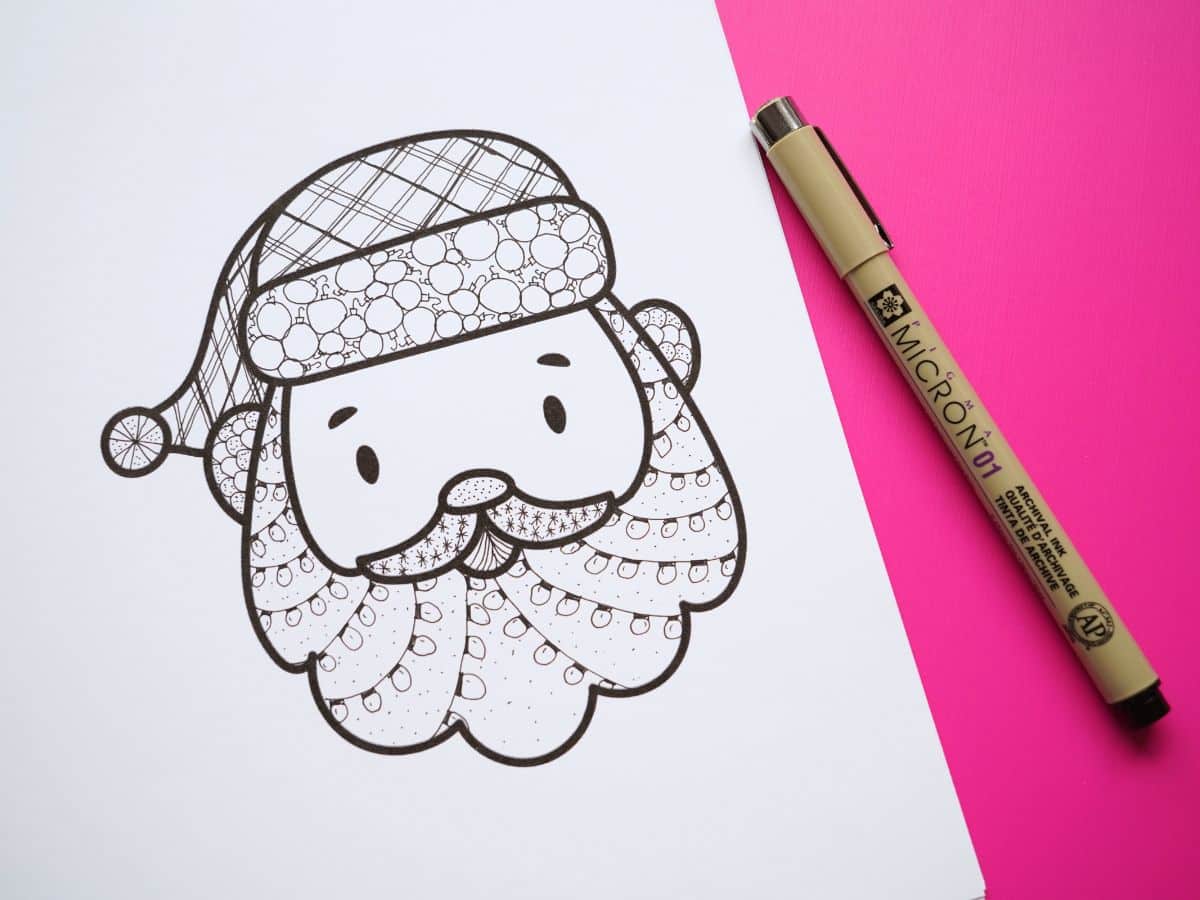 zentangle santa face card filled with doodles and beside a micron pen