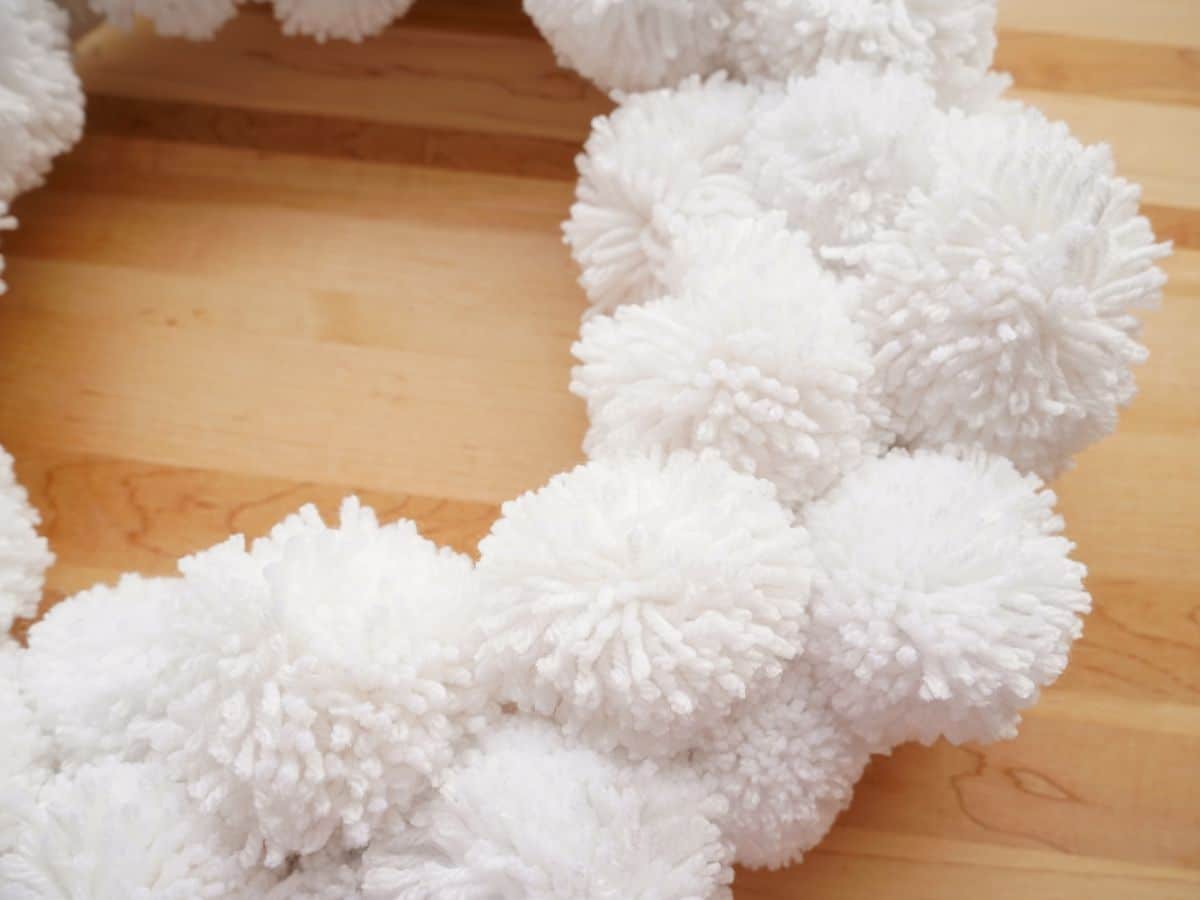 close up of white pom pom wreath with large and small pompoms