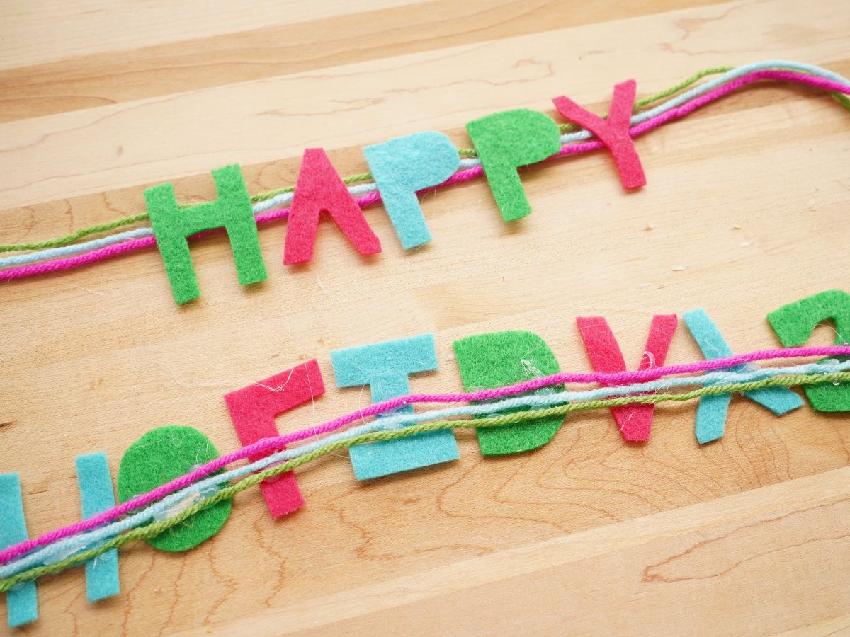 happy holidays felt letters glued on three pieces of yarn to make a garland