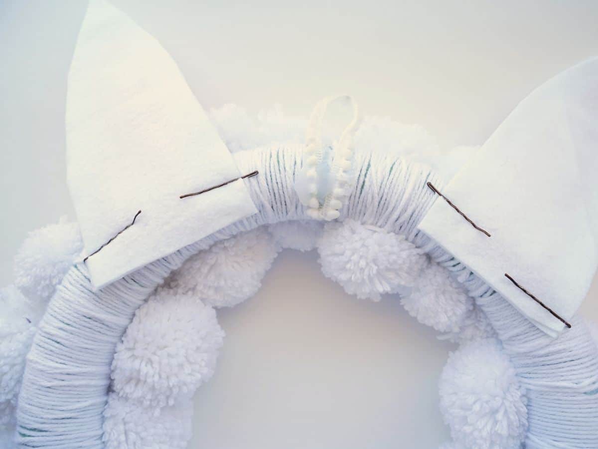 back side of easter bunny ears pinned onto white pom pom wreath
