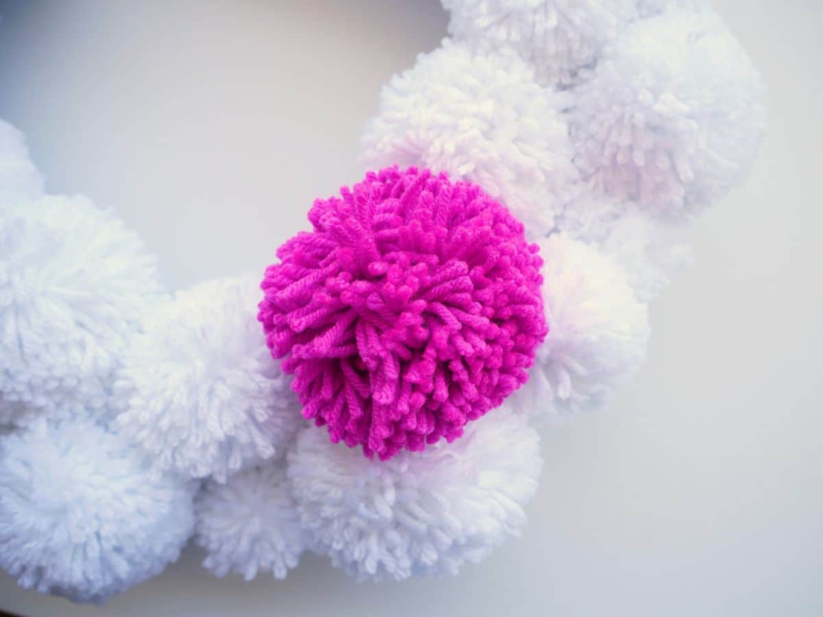 close up of pink pom pom pinned on white pom pom wreath