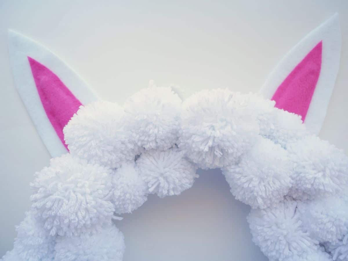 easter bunny ear on top of white pom pom wreath