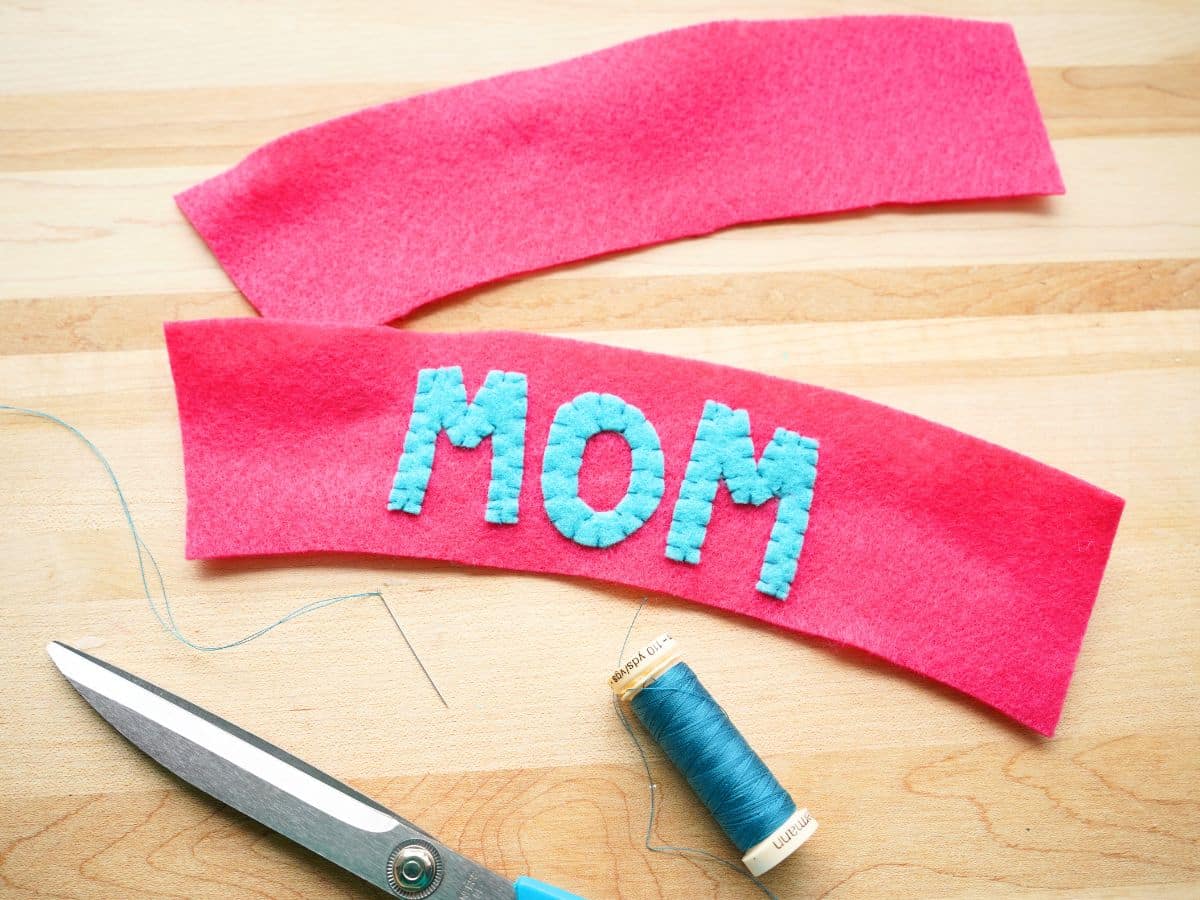 blue mom letters sewn onto pink felt coffee sleeve