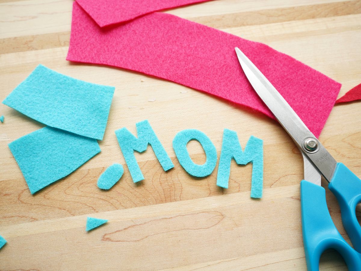 letters mom cut from blue felt and pair of scissors