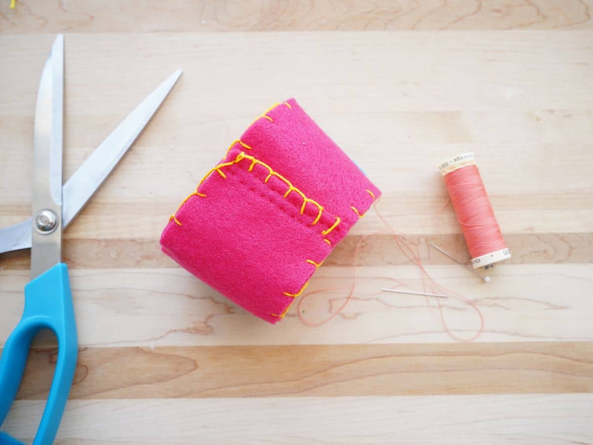 overlap in coffee cup sleeve sewn in place with thread and scissors