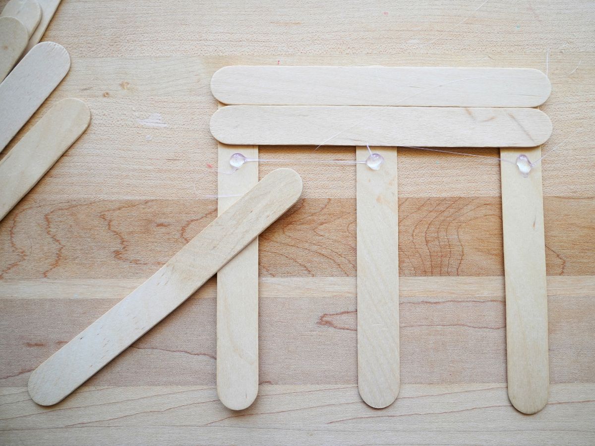 base of popsicle stick hanging bird feeder being made with glue gun
