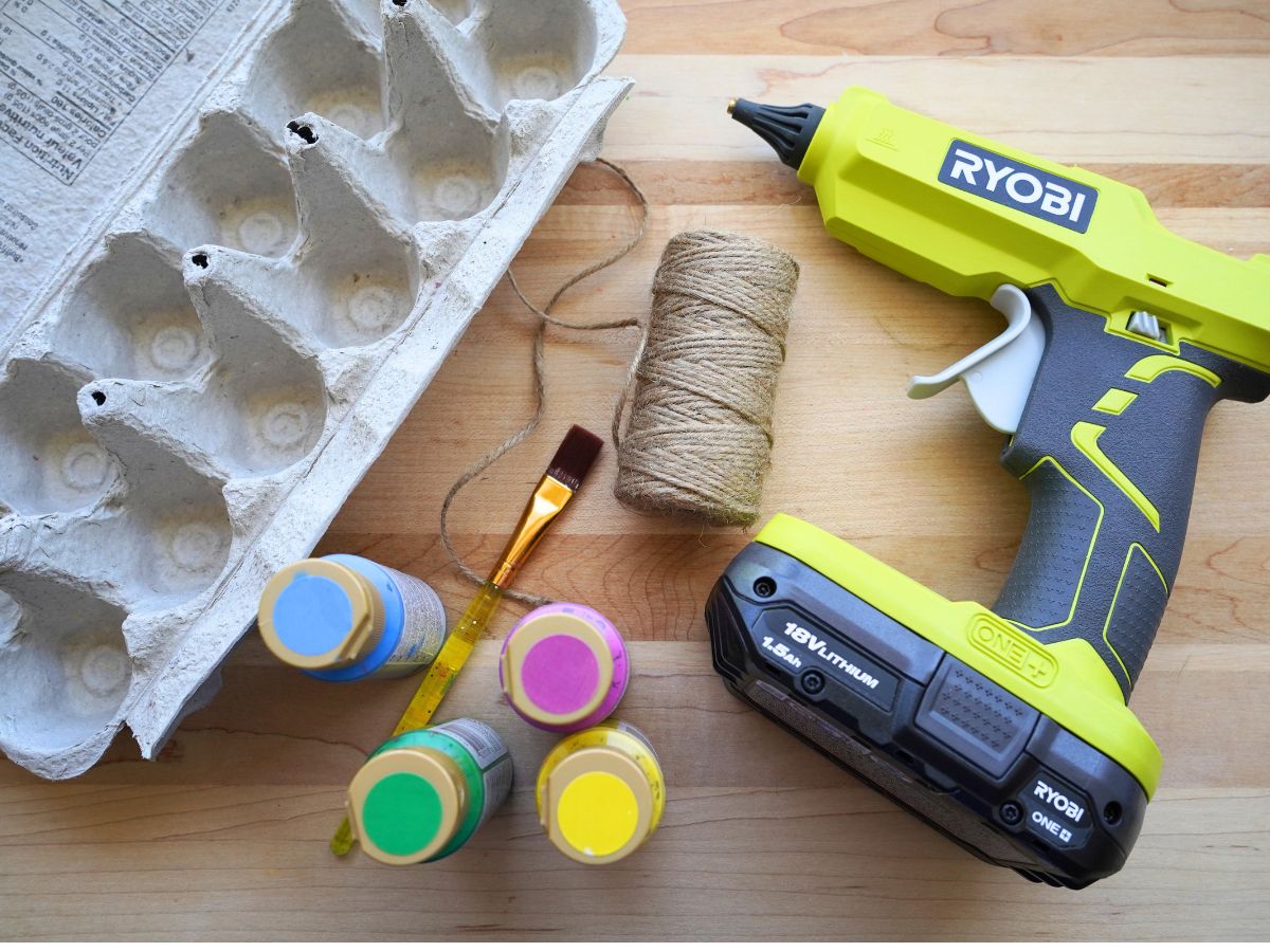 supplies for making hanging egg carton bird feeder - glue gun, egg carton, string, paints and paintbrush