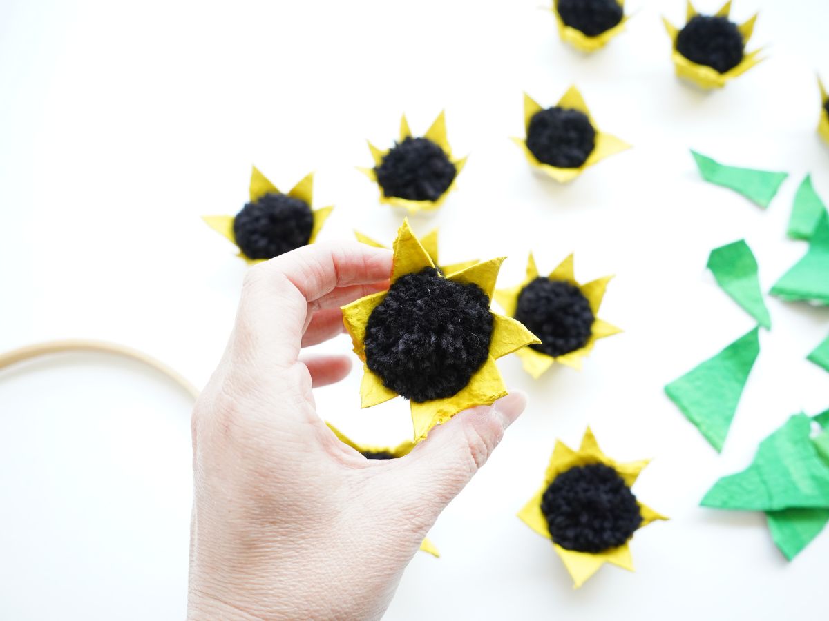 sunflower egg carton flower with black pompom center in person's hand