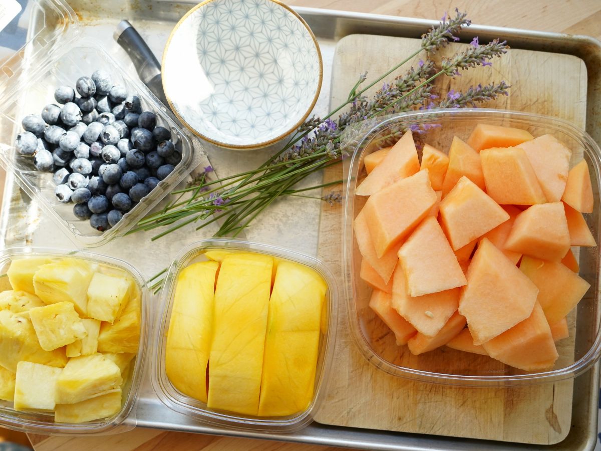 blueberries in container, small bowl, bunch of fresh lavender, canteloupe, mango and pineapple
