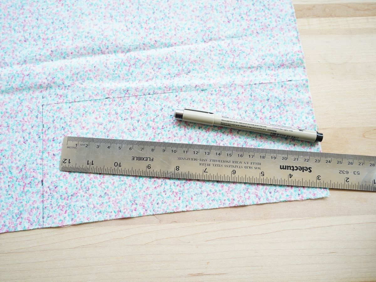 fabric scrap (wrong side facing) with ruler and black pen line drawn on