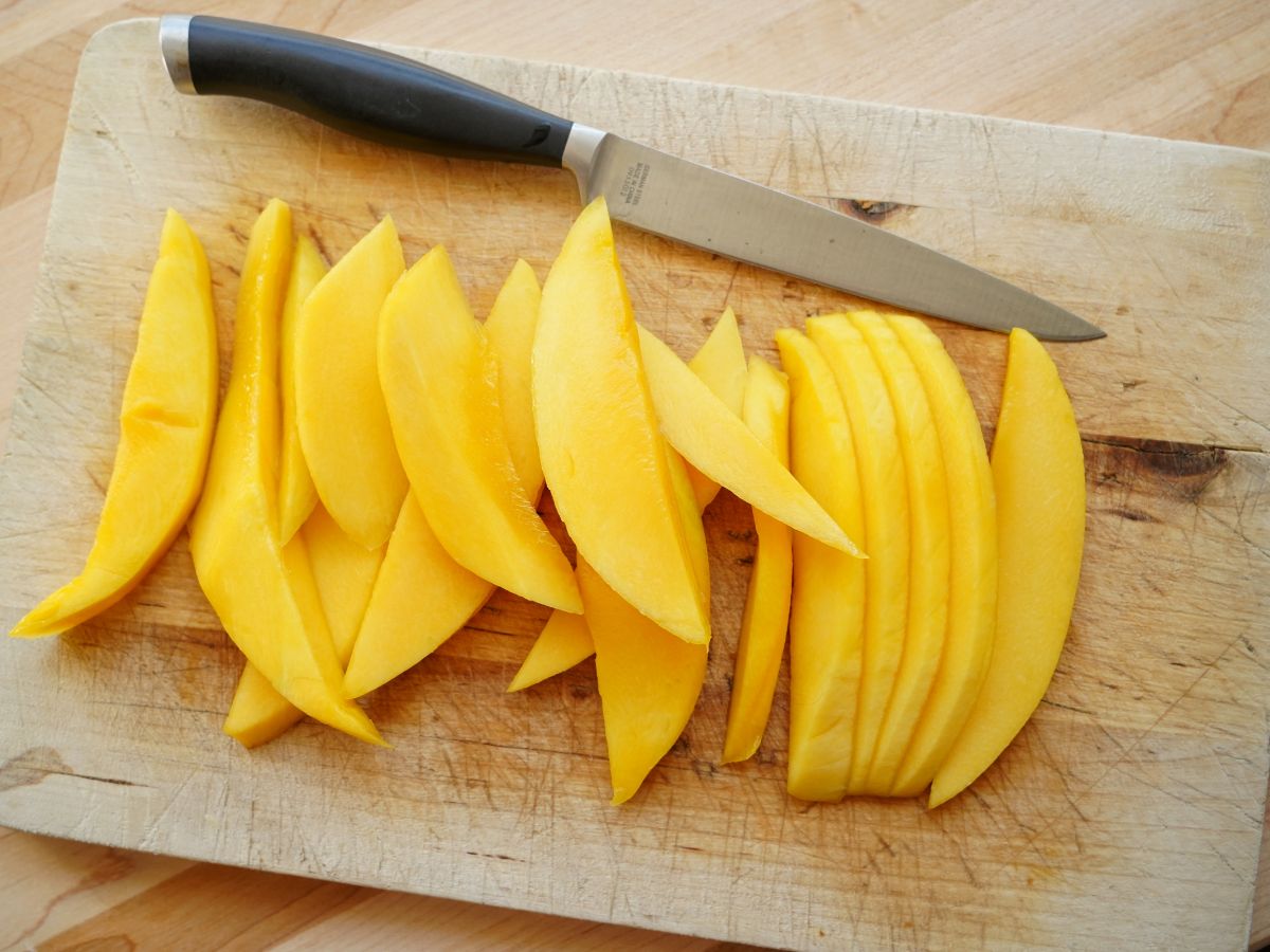 sliced mango on cutting board with knife