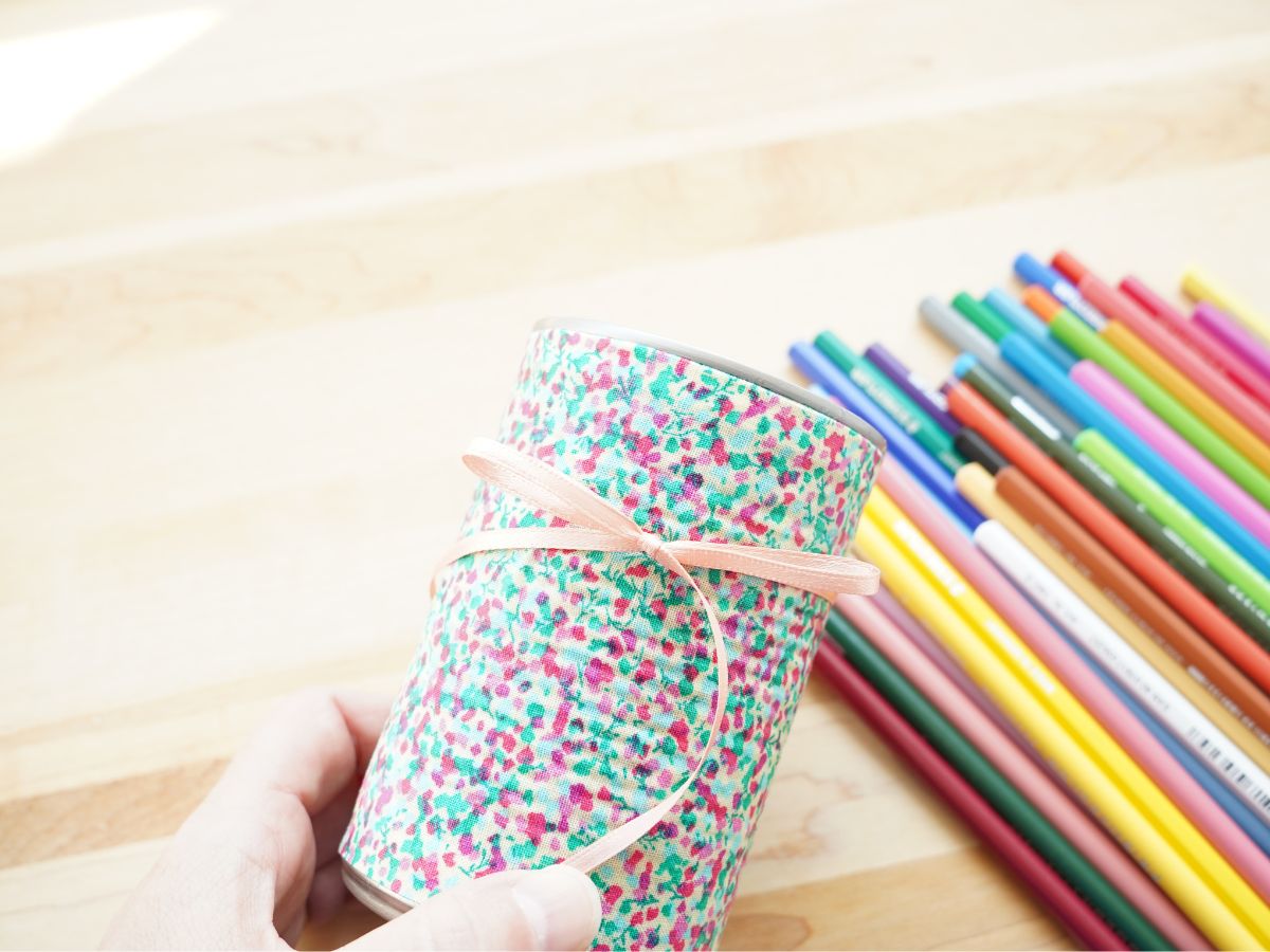 thin ribbon bow tied around diy pencil cup with pile of pencil crayons in the background