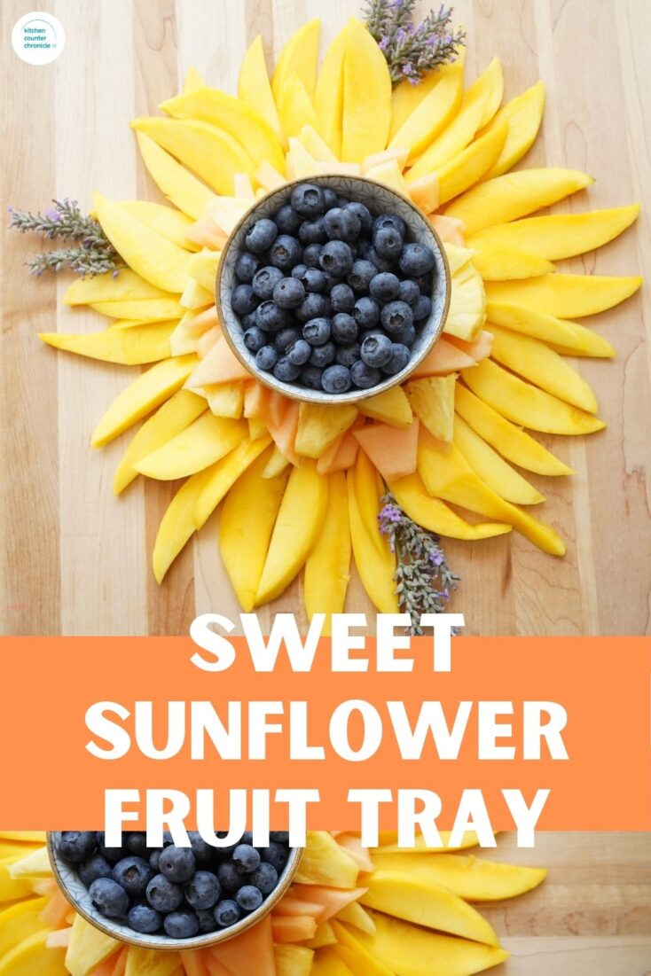 title sweet sunflower fruit tray with sunflower fruit tray made with mango slices, pineapple and cantaloupe with bowl of blueberries in middle and sprigs of lavender