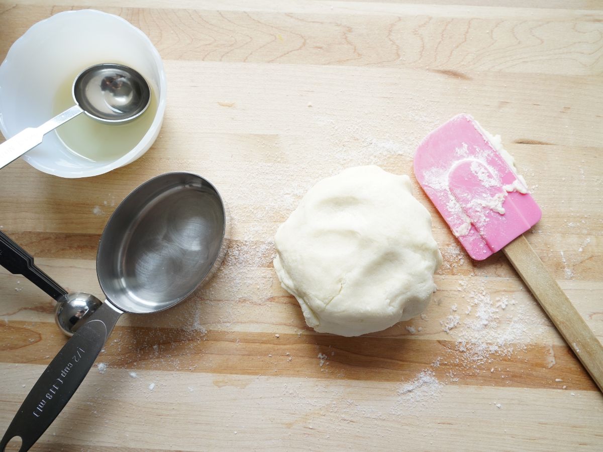 ball of salt dough on table with spatula and measuring spoons