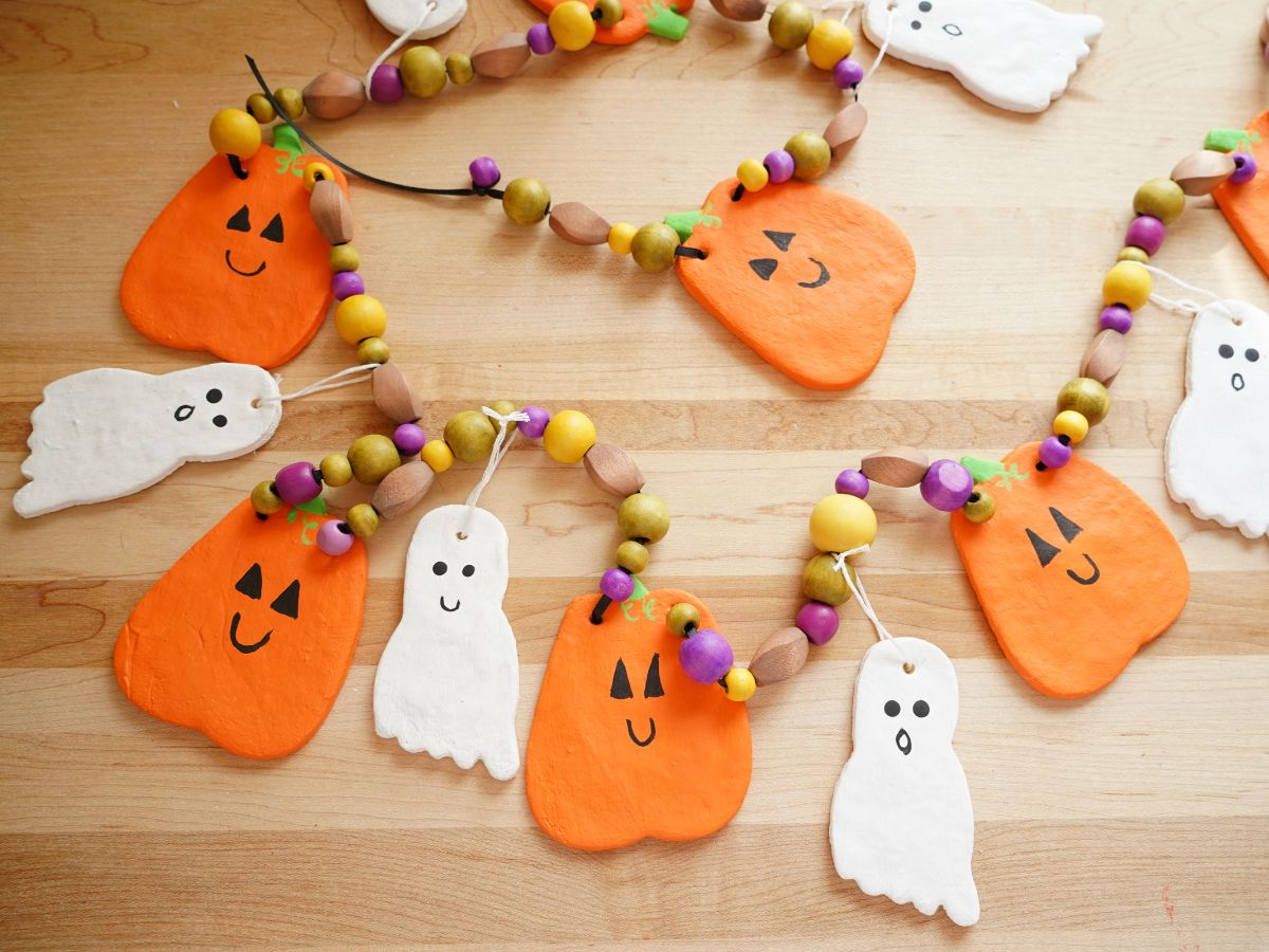 diy salt dough halloween garland with pumpkins and ghosts and wooden beads laying on table