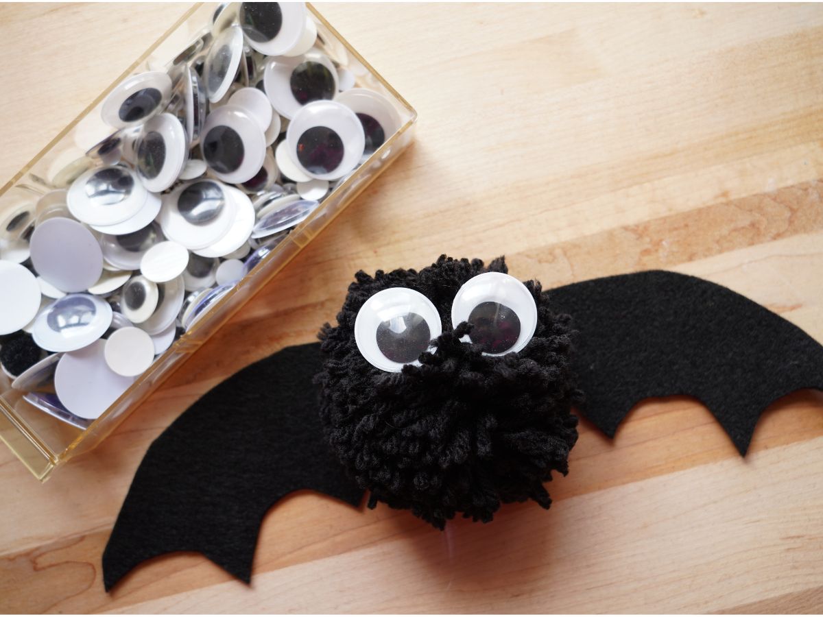 box of googly eyes with eyes glued on pom pom bat