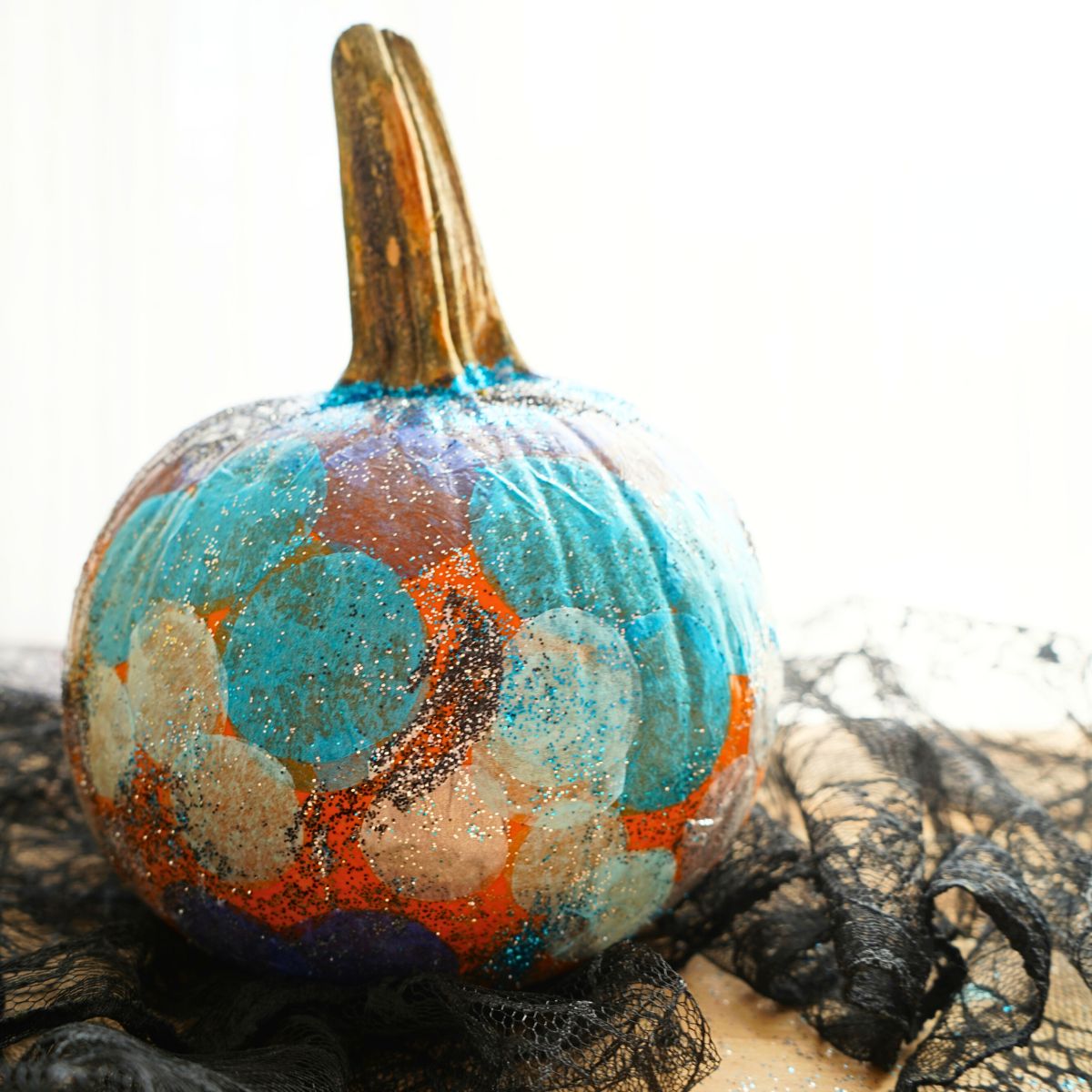 close up of diy glittery galaxy pumpkin sitting on black lace table cloth