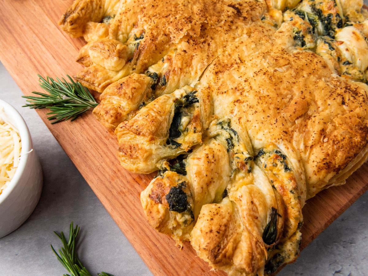 close up of folds of puff pastry with spinach dip at edge of christmas tree