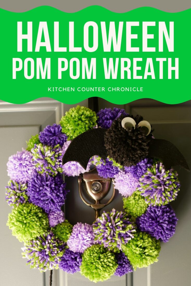 diy halloween wreath made from pom poms hanging on front door with title halloween pom pom wreath pin 2