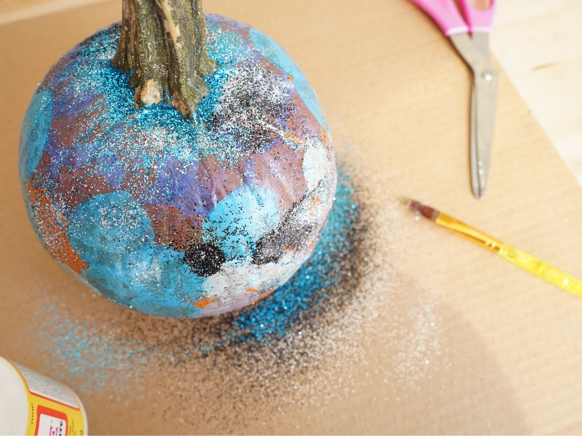 overhead shot of small pumpkin with blue and black and silver glitter on it