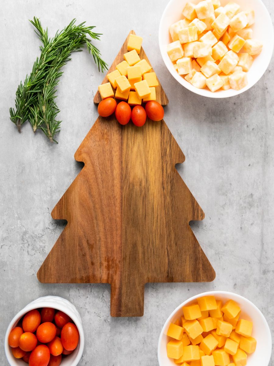 row of cherry tomatoes under cubes of gouda cheese on christmas tree charcuterie board