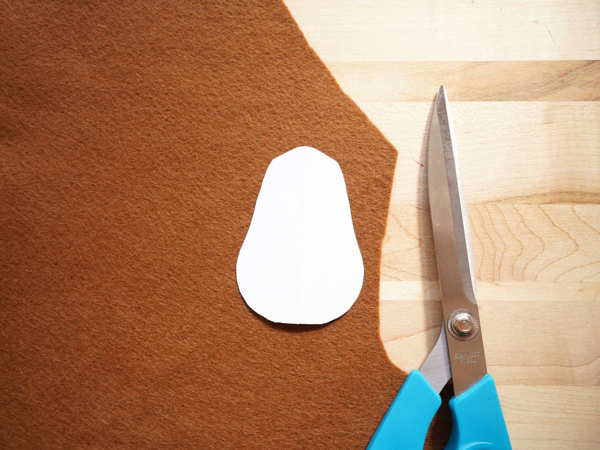sheet of brown felt with turkey body template on top with pair of scissors