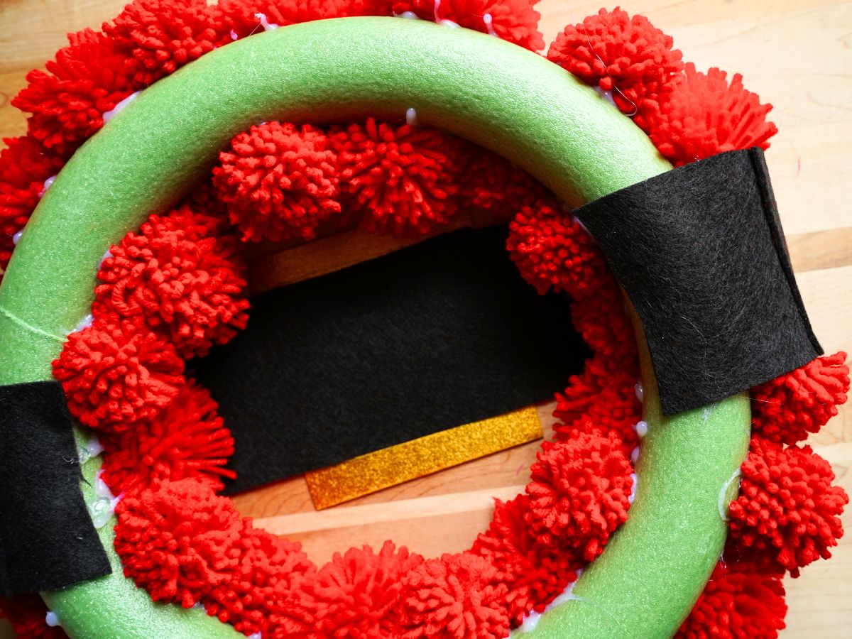 back side of Santa Claus pom pom wreath with felt belt being glued on the backside
