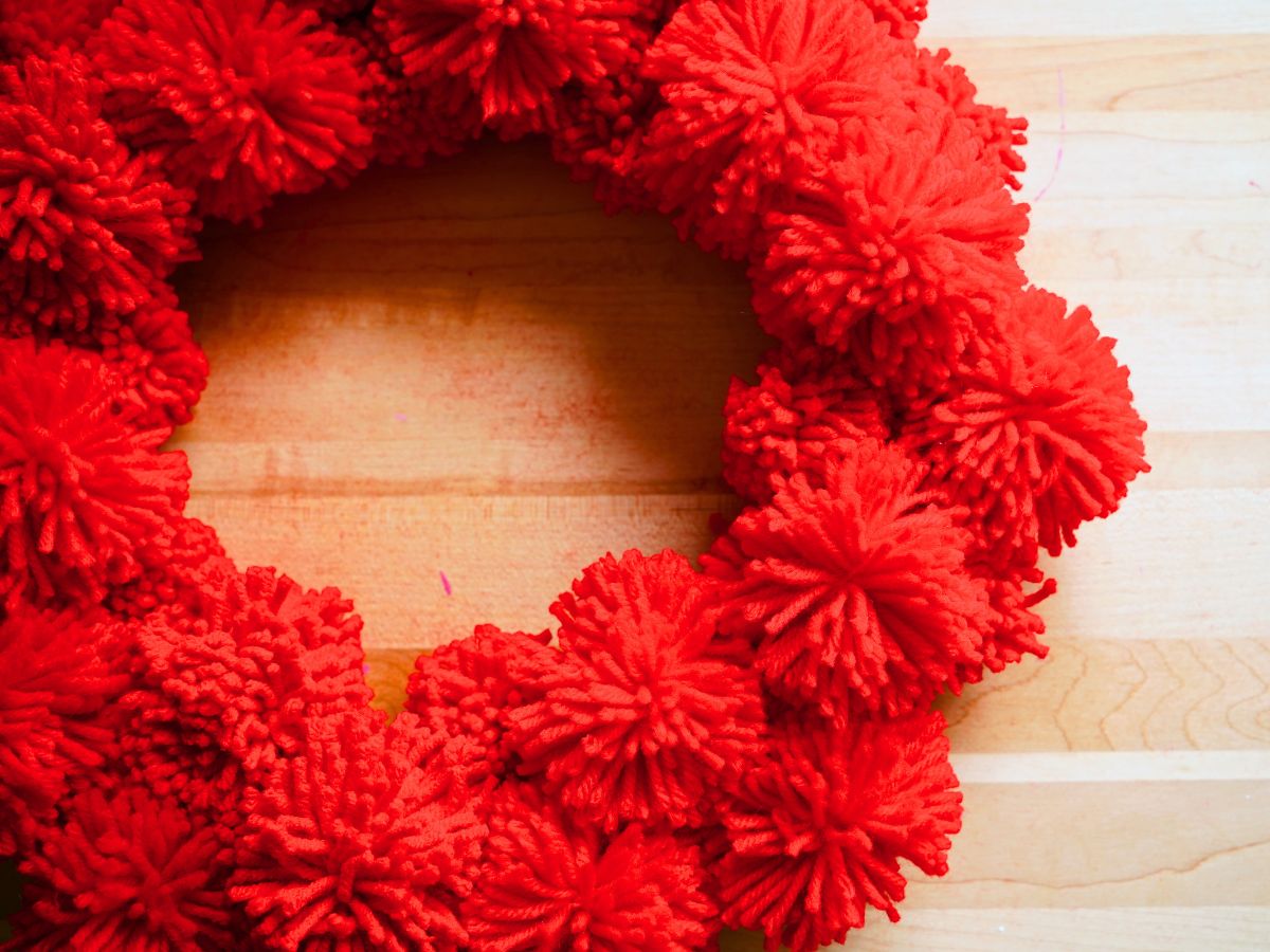 close up of red yarn pom poms glued on foam wreath form