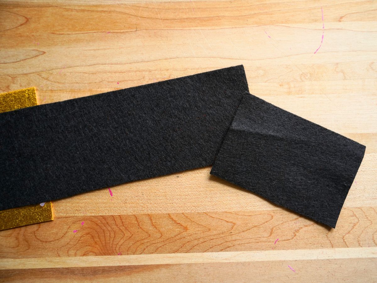 strip of black felt with shorter extension piece of black felt to be glued on