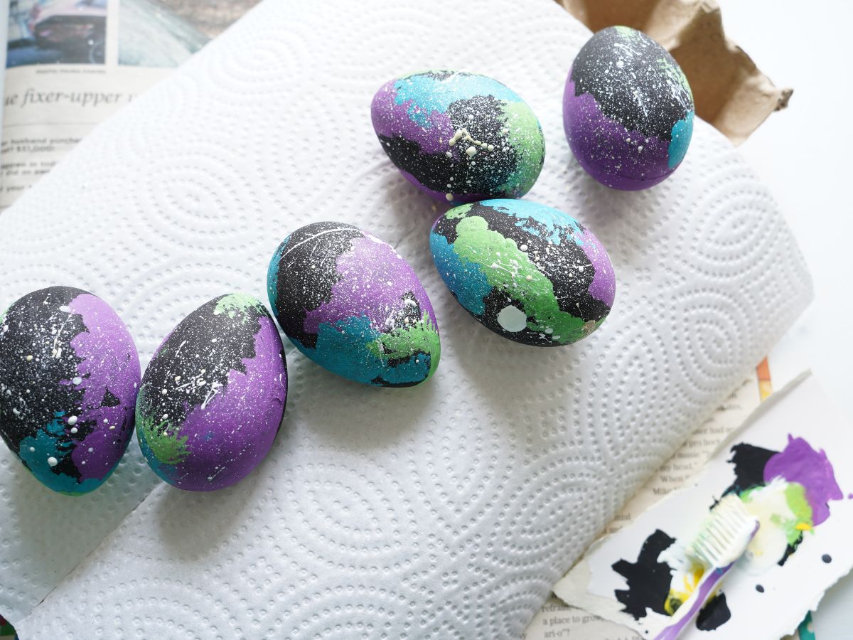 black easter eggs painted with toothbrush splatter to make starry galaxy