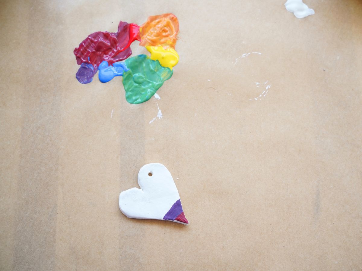 air dry clay heart with stripes of purple painted on and rainbow acrylic paints