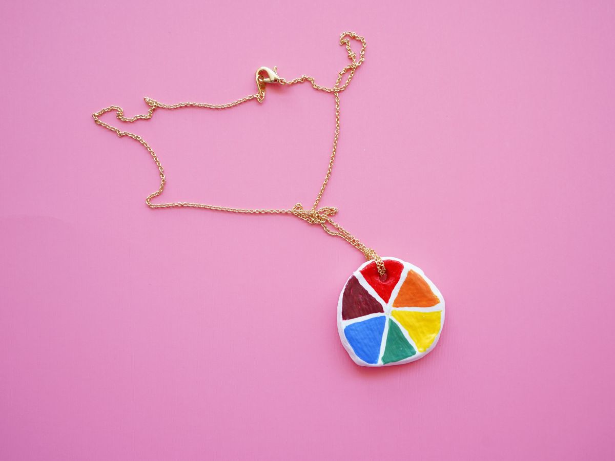 close up of air dry color wheel pendant on gold chain craft for tweens