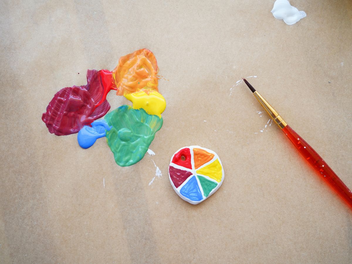 close up of painted color wheel necklace pendant with mixed acrylic paints and paintbrush