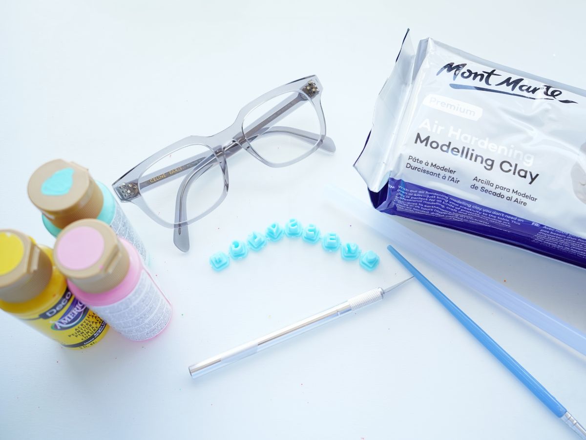 supplies for making an air dry eyeglass holder - paint, clay, letters, knife