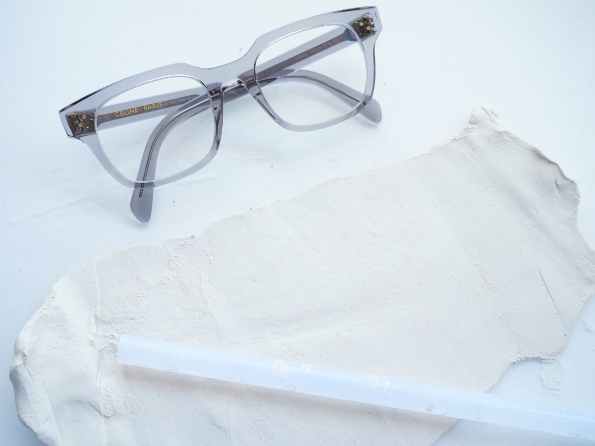 glasses laying beside rectangle of air-dry clay and glue stick rolling pin
